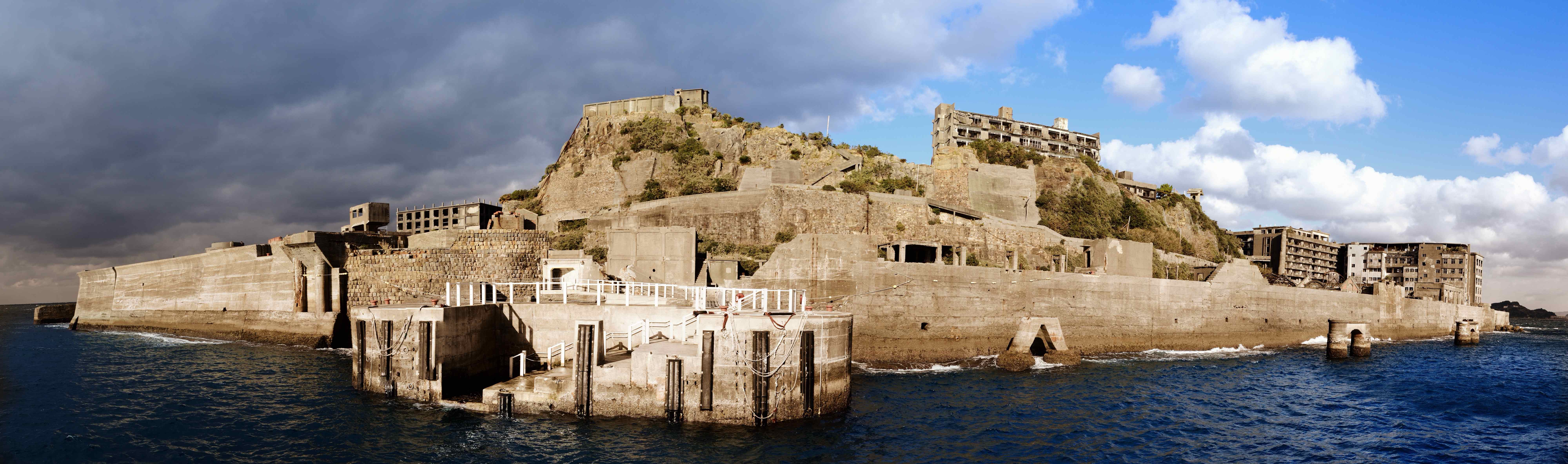 Contemporary aerial view of Hashima Island showing deteriorating concrete buildings surrounded by seawalls, off the coast of Nagasaki